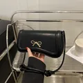 Klassische schwarze Leder Umhängetasche mit feiner goldener Metallschleife - Schwarz