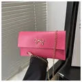 Hot pink envelope clutch with gold bow detail and detachable metal chain strap - Pink