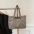 Détail d'un sac cabas en cuir gris grainé avec poche latérale sur un cintre en métal - Gris