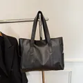 Détail d'un grand cabas en cuir noir minimaliste avec texture fine et poche latérale pratique - Noir