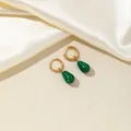 Dettaglio dei orecchini in malachite a goccia con cerchi dorati lucidi su seta beige - Verde