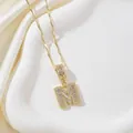 Vue détaillée du pendentif lettre M doré serti de zircons sur un tissu en soie - Lettre M