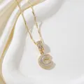 Golden letter C pendant necklace with sparkling cubic zirconia on silk background - Letter C