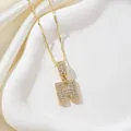 Collier lettre H doré orné de zircons cubiques sur un tissu en soie beige - Lettre H