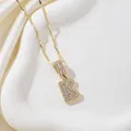 Détail du pendentif lettre K doré serti de zircons sur un fond en soie élégant - Lettre K