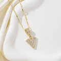 Détail d'un collier doré en forme de V serti de zircons et d'une pierre de taille baguette - Lettre V