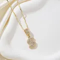 Collier avec pendentif lettre S dorée serti de zircons sur un plateau blanc élégant - Lettre S