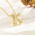 Detailed view of polished gold letter K pendant on a box chain over white stone - K (With Box Chain)