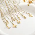 Close-up of gold plated initial pendant necklaces displayed on a white ceramic tray - Capital Letter A / Gold