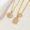 Dettaglio di collane placcate in oro con lettere B ed E e pendenti con zirconi lucidi - Lettera E