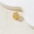 Makroaufnahme von vergoldetem Würfelanhänger mit Buchstabe K und Zirkonia auf Beige - Buchstabe K / Gold