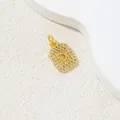 Macro shot of gold square letter D pendant with cubic zirconia and polished step edges - Letter D