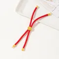 Close-up of handmade red braided cord bracelet with central carved gold bead ornament - Red