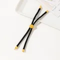 Detail of adjustable black braided cord bracelet with gold charm on a gift card - Black
