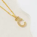 Macro view of gold letter C pendant with crown detail and inlaid cubic zirconia stones - Letter C
