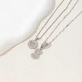 Silver-colored initial S pendant necklaces with sparkling stones on textured background - Letter S / Silver