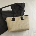 Beigefarbene Strohtasche mit schwarzem Lederbesatz und Henkeln für den Sommerstil - Schwarz