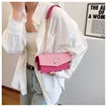 Detail of pink plaid crossbody bag with gold M logo and chain strap on a model - Rose Red