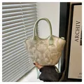 Nahaufnahme der floralen Bestickung und des mintgrünen Ledergriffs an der Handtasche - Grün