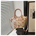 Detail showing elegant floral embroidery and pink handle on a chic trapezoid crossbody bag - Pink