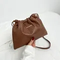 Brown woven drawstring crossbody bag with bucket style and long braided shoulder strap - Brown
