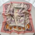 Eleganter quadratischer Seidenschal mit Blumenmuster und rosa Rand auf einem Tisch - Rosa