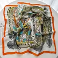 Detalle de un pañuelo de seda con estampado de hojas y borde naranja en una mesa - Rojo Anaranjado