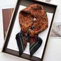 Elegant silk-like square scarf with orange paisley print on display tray for women - Orange Red