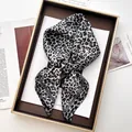 Macro detail of silk-feel leopard print scarf with grey rolled edges in a gift box setup - Gray
