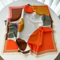 Detailed overhead view of a silk square scarf with geometric color block patterns and texture - Orange Red