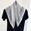 Detail of a black and white paisley silk scarf with polka dot patterns and satin texture - White