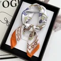 Satin silk scarf with chain print and orange border displayed on a fashion magazine - Orange Red