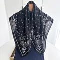 Close-up of black and white paisley silk-like scarf with bohemian patterns on a hanger - Black