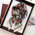 Détail d'un foulard carré à fleurs paisley avec texture soie sur plateau en bois - Champagne Rouge Bleu Cachemire