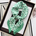 Carré de soie vert à damier et motif floral sur un plateau vintage avec un magazine - vert clair