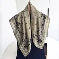 Detail of olive green paisley square scarf with star patterns on a wooden hanger - Olive Green