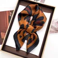 Dettaglio di un foulard in raso leopardato annodato a fiocco su rivista di moda - Marrone scuro