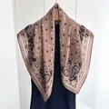Detalle de un pañuelo de seda marrón con motivos paisley vintage en percha de madera - Rosa