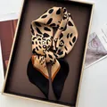 Dettaglio macro della sciarpa in seta leopardata con finitura satinata e bordo nero fine - Bordo Nero
