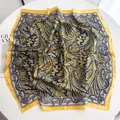 Detalle de pañuelo cuadrado de satén paisley con borde amarillo en mesa blanca - Square Style / Amarillo