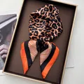 Detail of leopard print silk scarf with orange stripes displayed on a tray - Orange Red