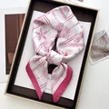 Elegant white silk scarf featuring pink seashell and starfish prints on a display tray - Pink
