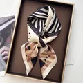 Elegant zebra and geometric print silk scarf displayed on a luxury jewelry tray - Zebra Khaki