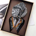 Detailed shot of black and white paisley silk twilly with orange trim in a gift box - Black