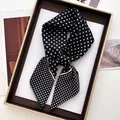 Dettaglio di un foulard di seta nero a pois bianchi in una confezione regalo dorata - Sciarpa Lunga Stretta / Nero