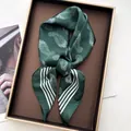 Close-up of silk scarf with white paisley pattern in an elegant gold-trimmed gift box - Green
