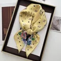 Close-up of yellow silk scarf featuring paisley floral prints and heart pattern details - Yellow