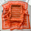 Detailed view of bright orange silk scarf featuring white paisley patterns and striped edges - Orange White Paisley (5)