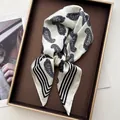 Elegante pañuelo de seda con estampado paisley negro y bordes de rayas en una bandeja - Blanco
