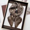 Detail view of brown satin scarf with white paisley pattern in a luxury display tray - Large Square / Khaki